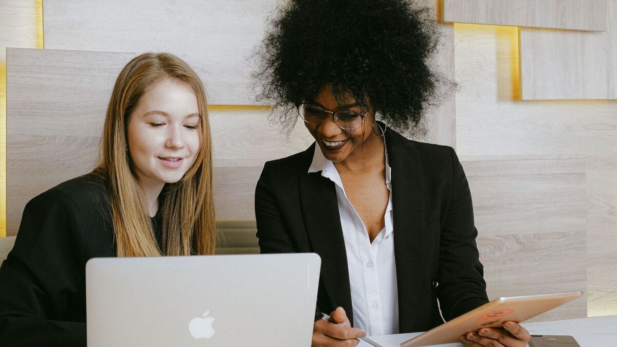 Mulheres sentadas à mesa em ambiente de trabalho.