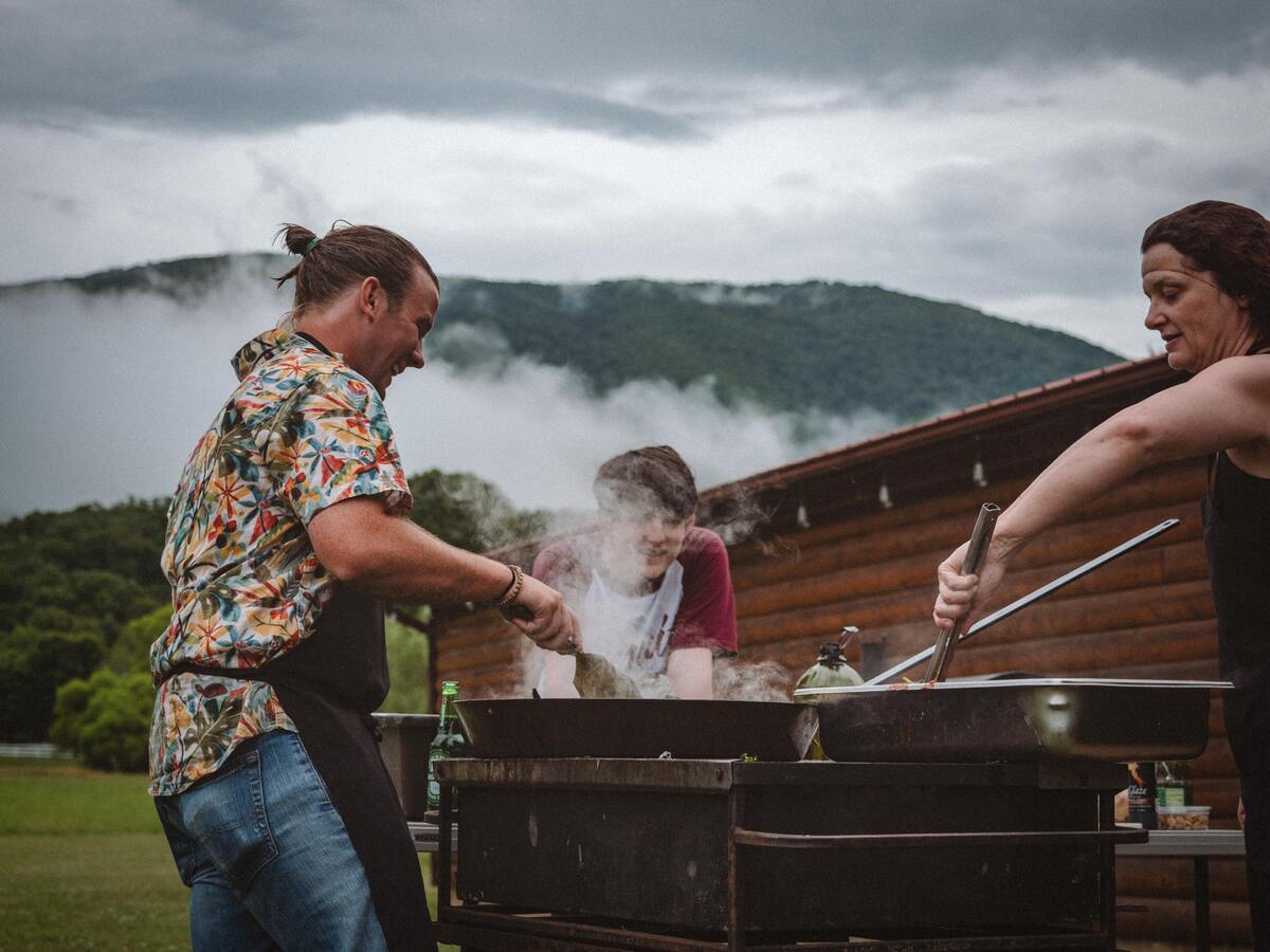 Três pessoas fazendo churrasco.