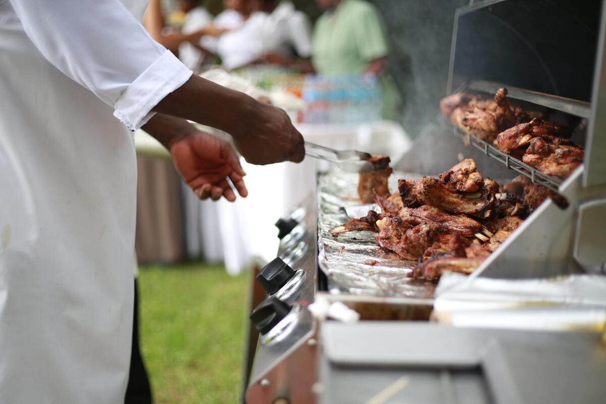 Homem faz churrasco em uma churrasqueira profissional.