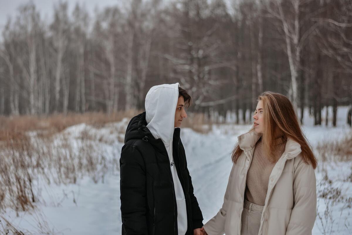 Casal se olhando em um campo coberto de neve.