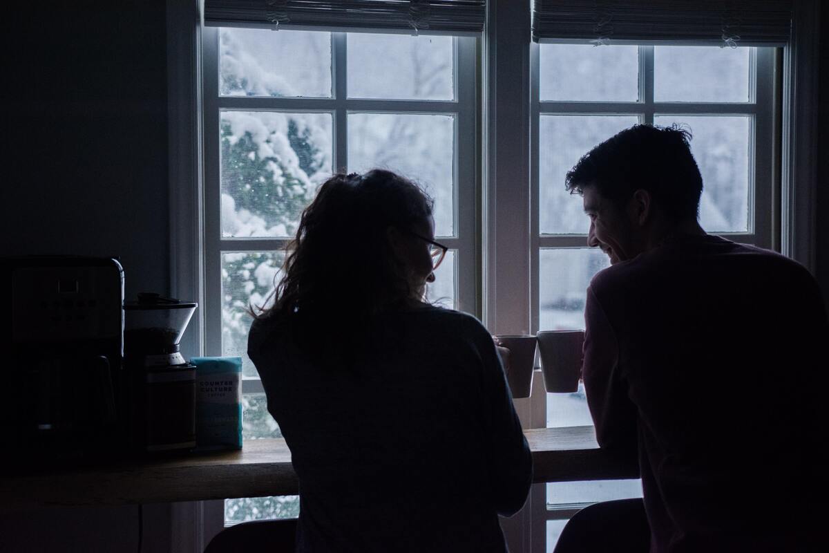 Silhueta de um casal brindando com xícaras de café. 