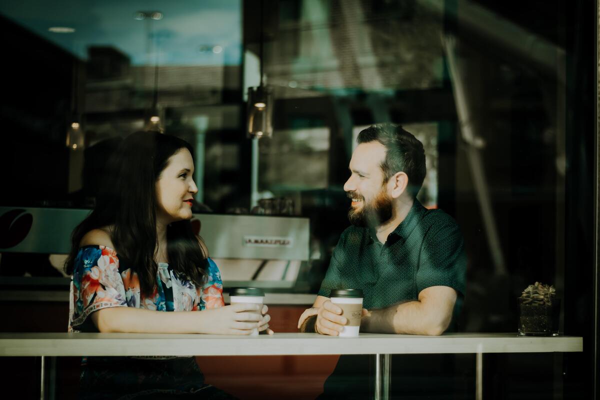 Casal sentado conversando enquanto toma café.