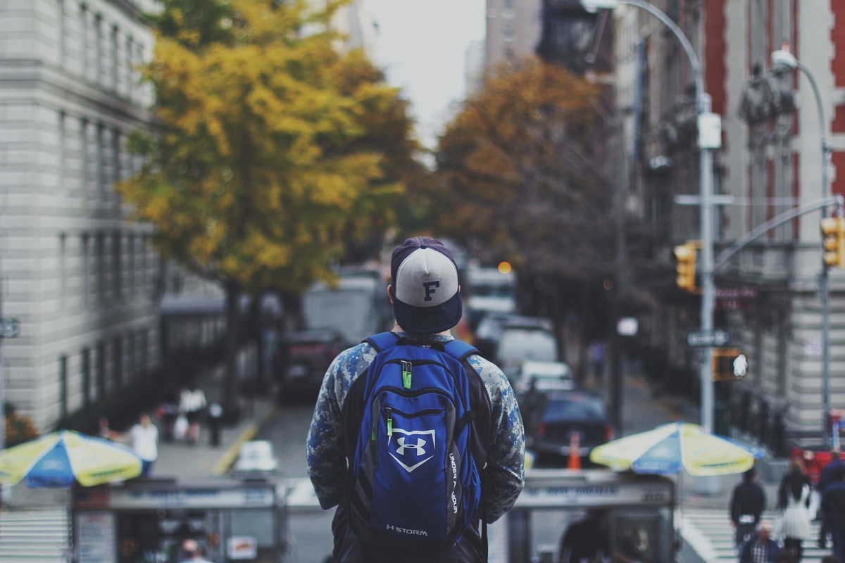 Homem com mochila olhando ao horizonte, parecendo à procura de algo.