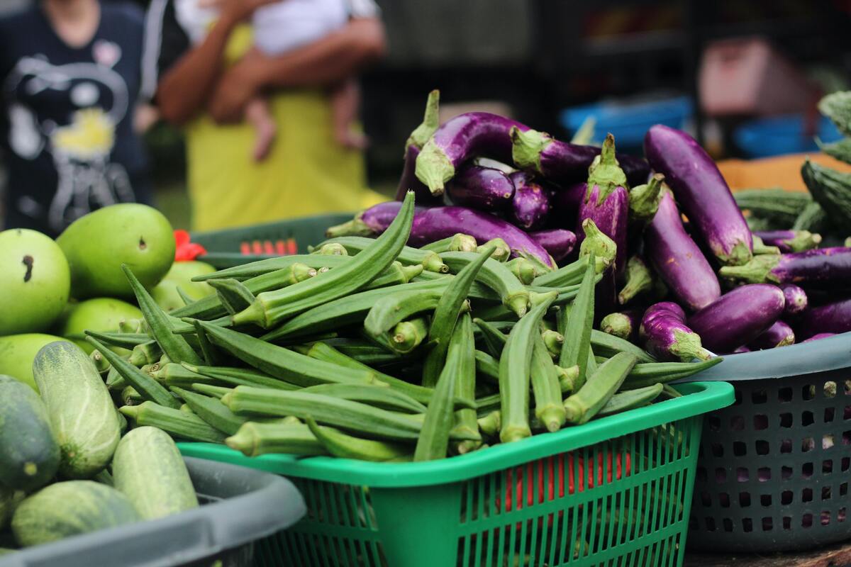 Caixa com quiabos em meio a outros vegetais.