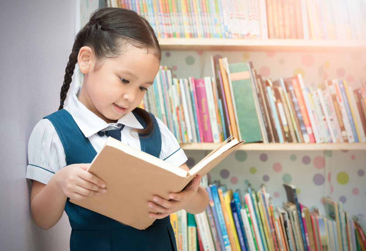 Criança lendo em biblioteca de escola