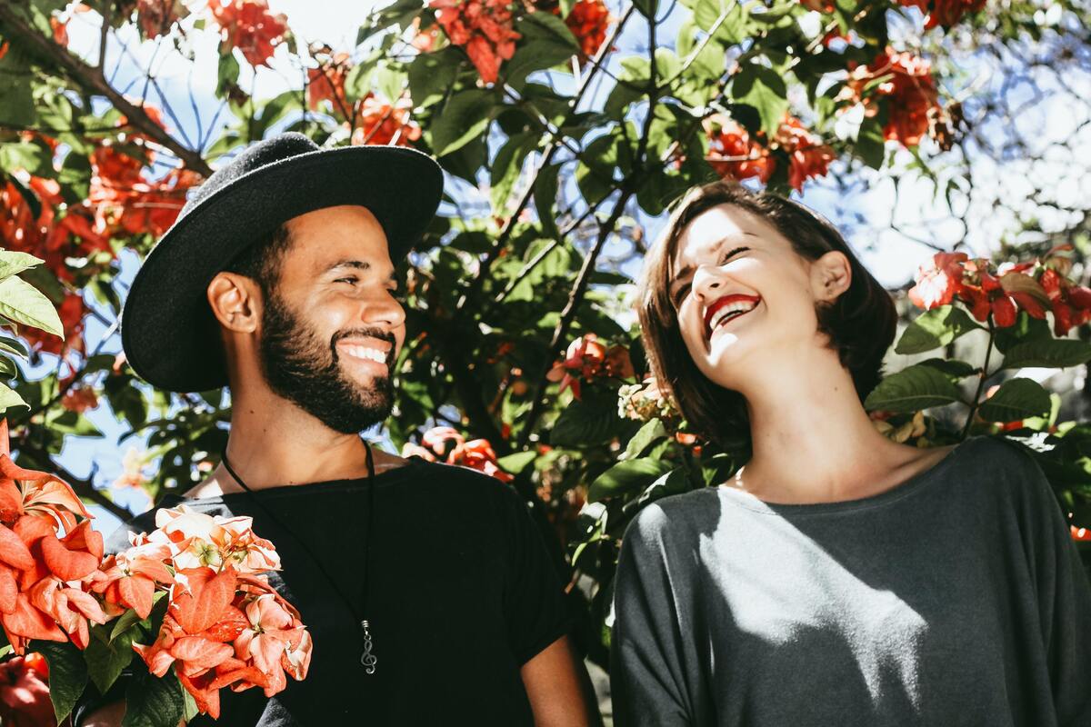 Casal entre as flores, sorrindo um para o outro.