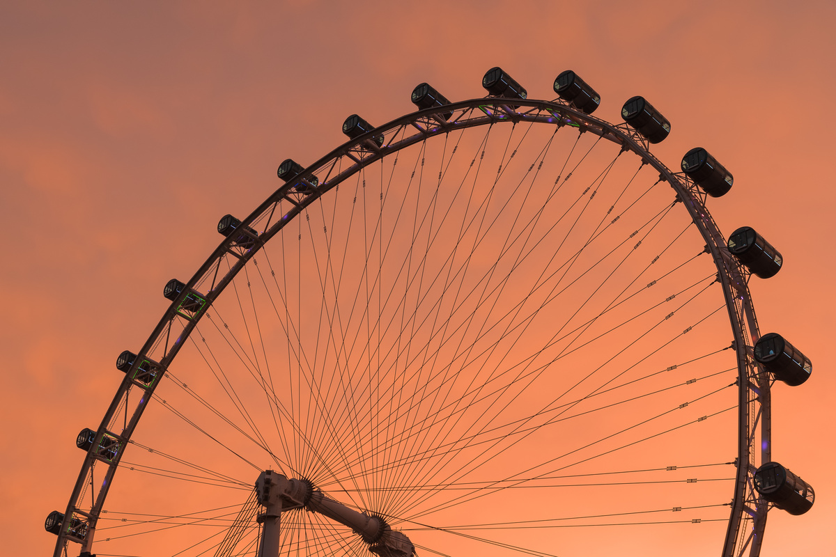 Roda gigante vista em meio a por do sol alaranjado.