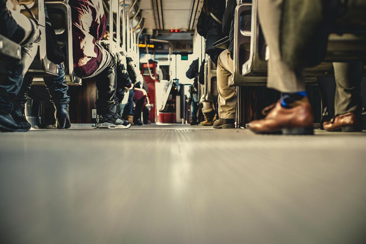 Visão dos pés das pessoas dentro do ônibus.