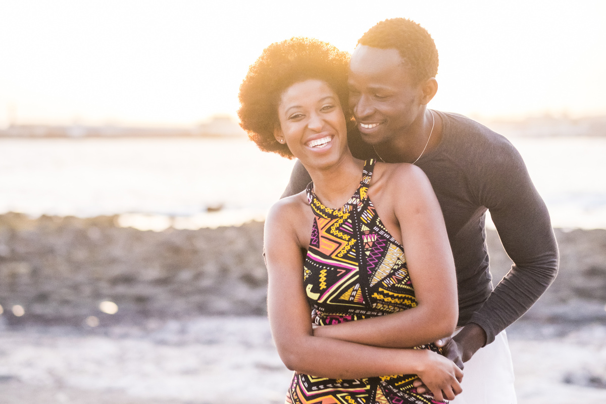 Casal se abraçando enquanto sorriem em frente ao sol, representando a Casa 5 em Virgem e os relacionamentos.