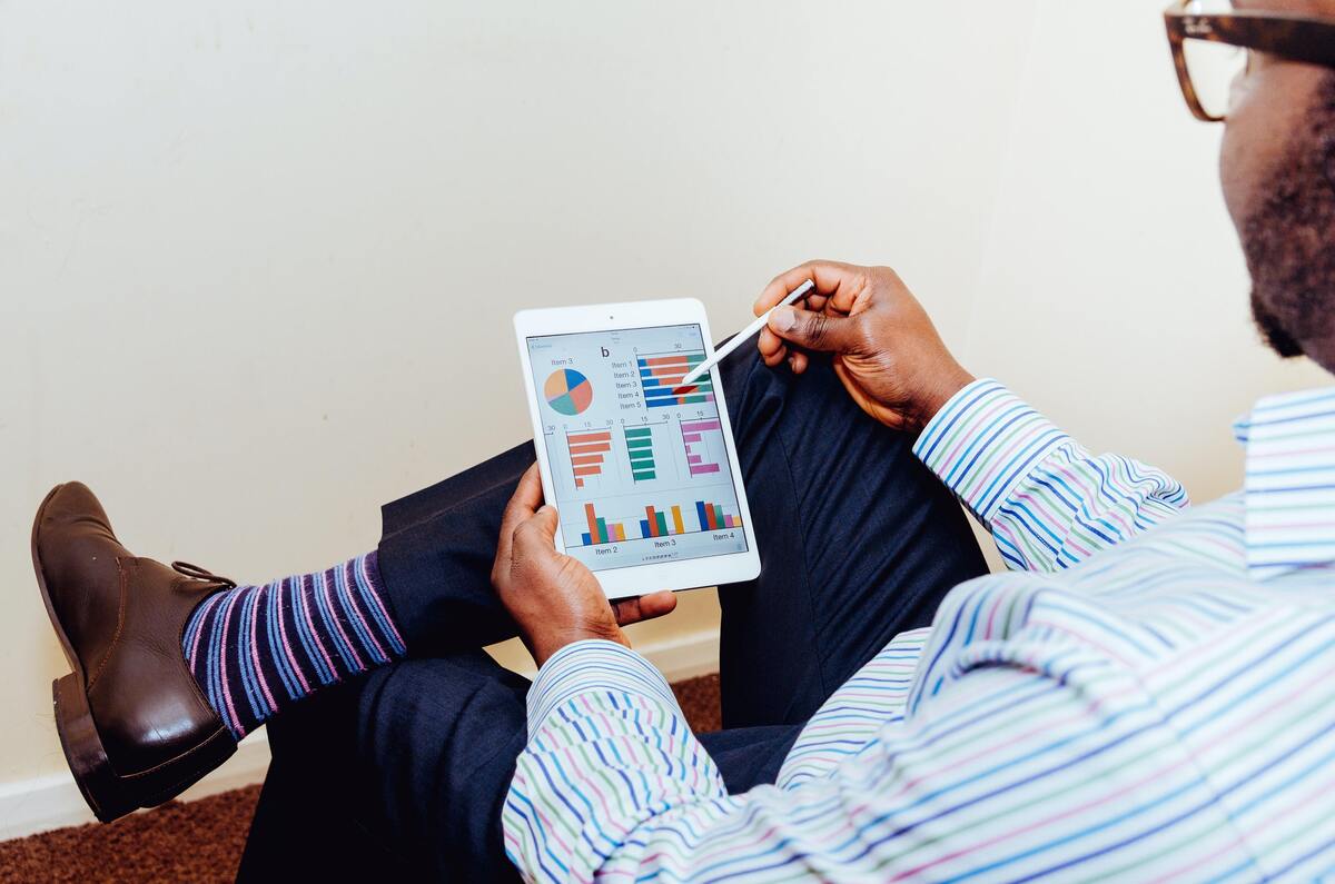 Homem em horário de trabalho avaliando gráficos no tablet.