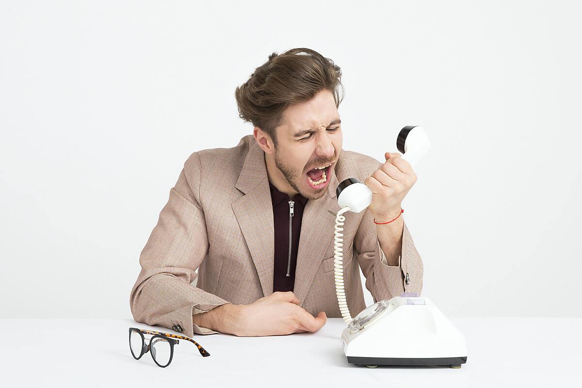 Homem gritando com um telefone na mão.