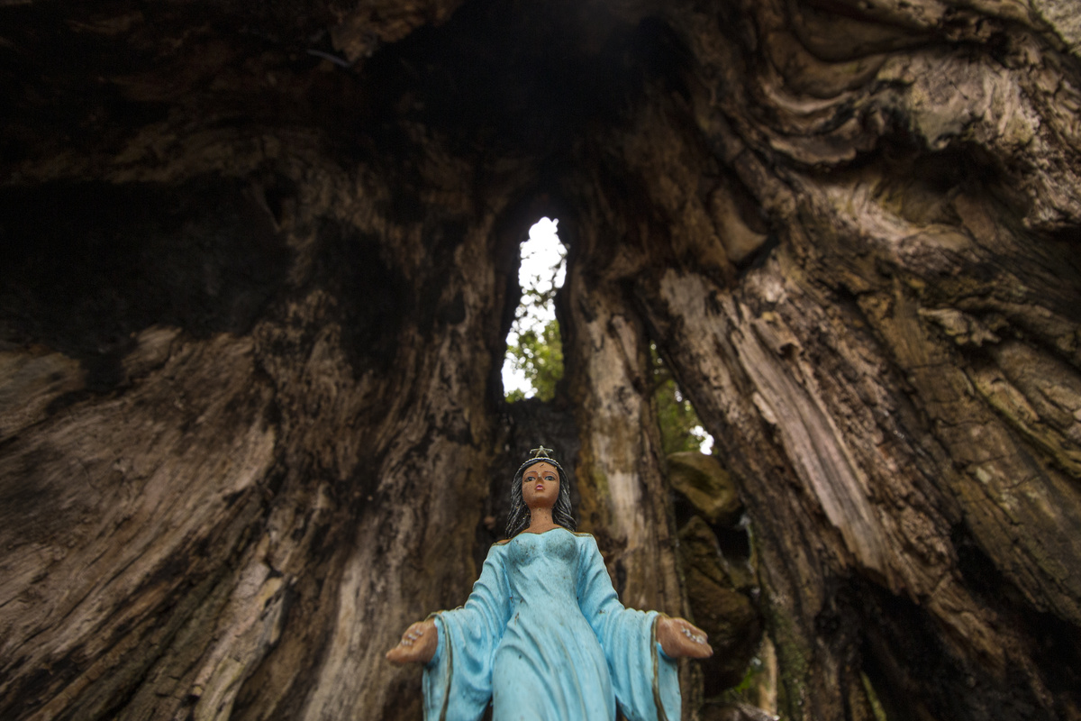 Estatua de Iemanjá vista de baixo, dentro de estrutura cavernosa e escura.