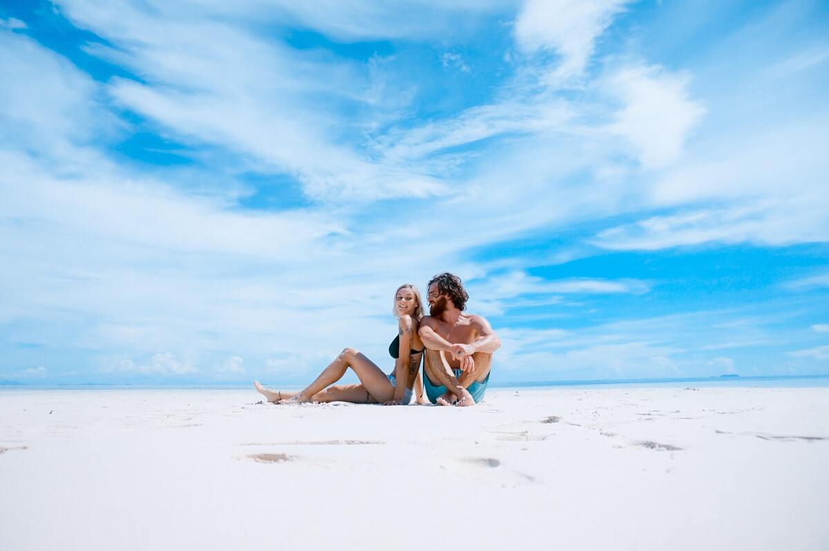 Casal sentado na areia da praia.