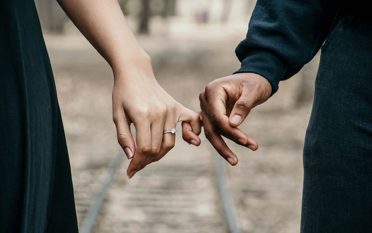 Casal com dedos entrelaçados.