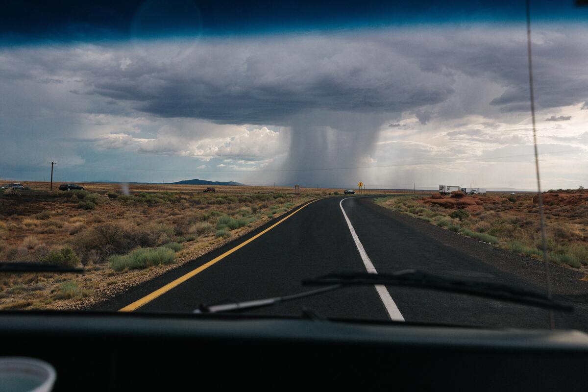 Tornado acontecendo na linha do horizonte, no final de uma rua. 