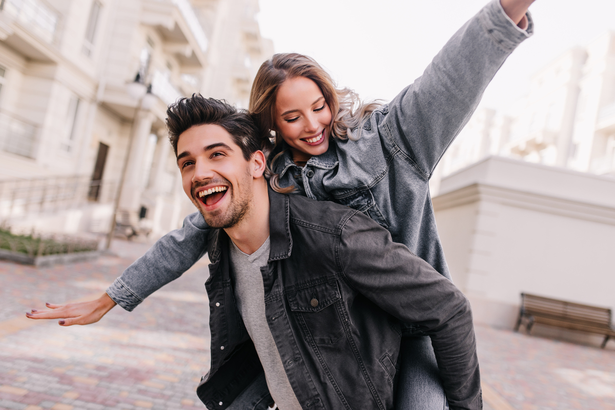 Um homem com uma mulher no colo e ambos sorrindo