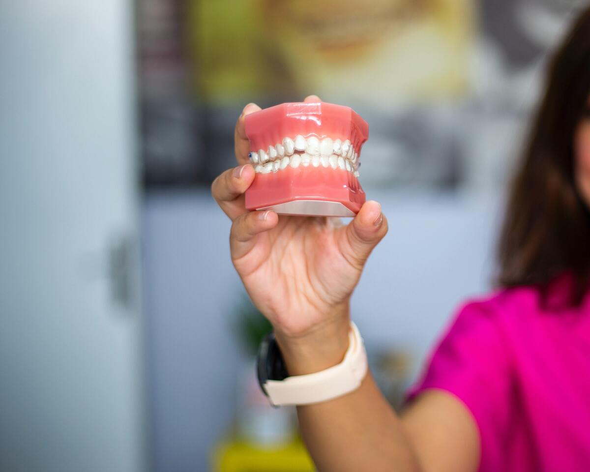 Mulher segurando dentadura com a mão