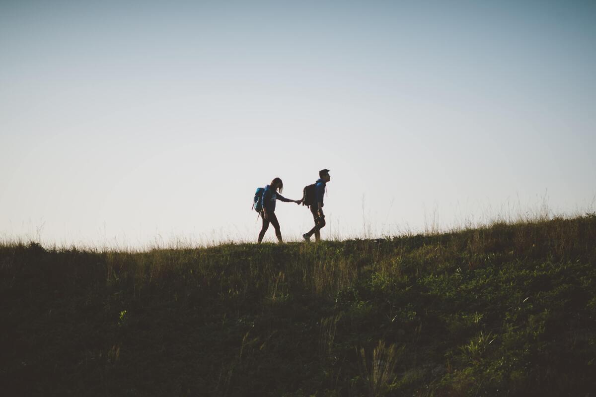 Casal escalando um morro. 