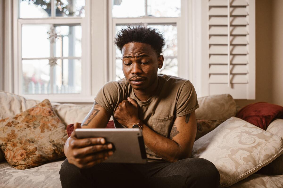 Homem sentado em um sofá com tablet na mão