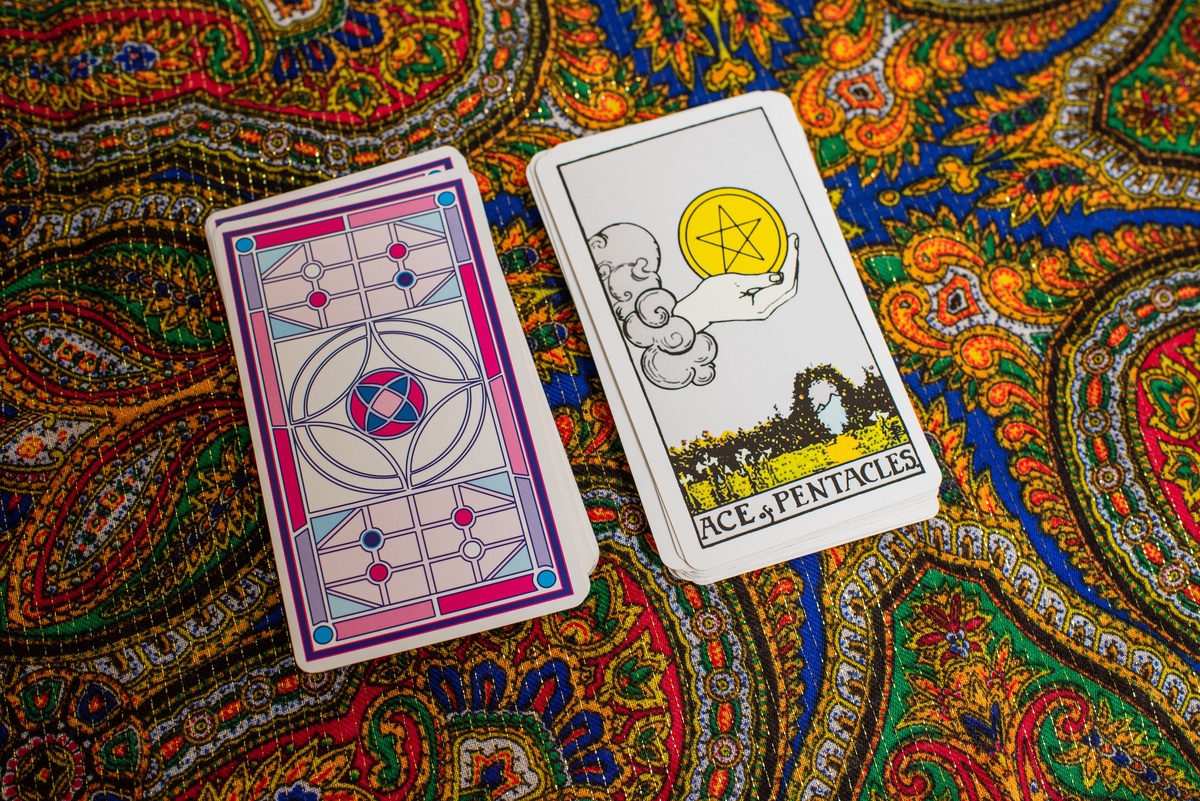 Carta As de Ouros ao lado de pilha de cartas de Tarot.