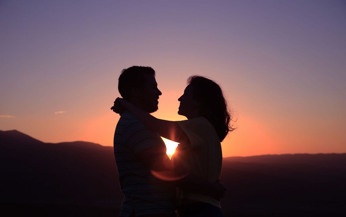 Casal abraçado ao pôr do sol.