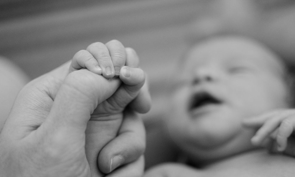 bebê recém-nascido segurando mão da mãe