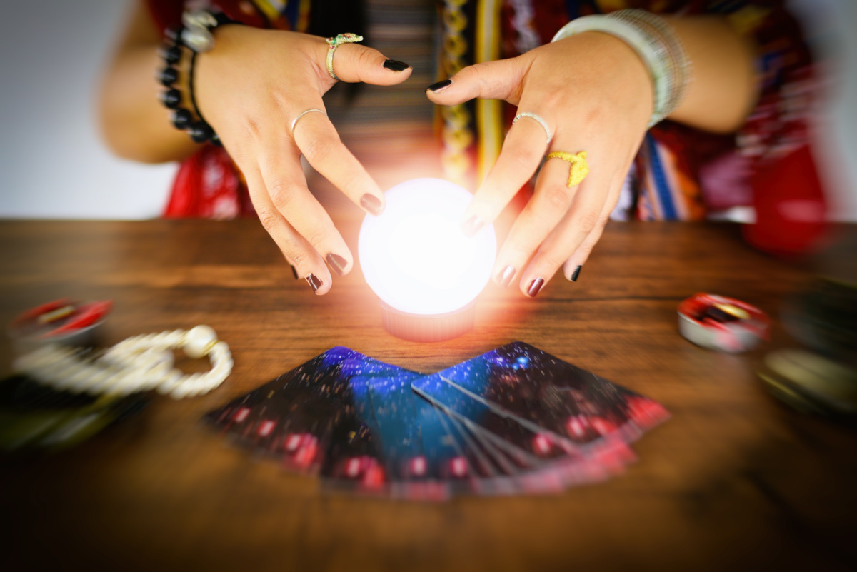 Cartomante lendo bola de cristal, com cartas de tarot à volta