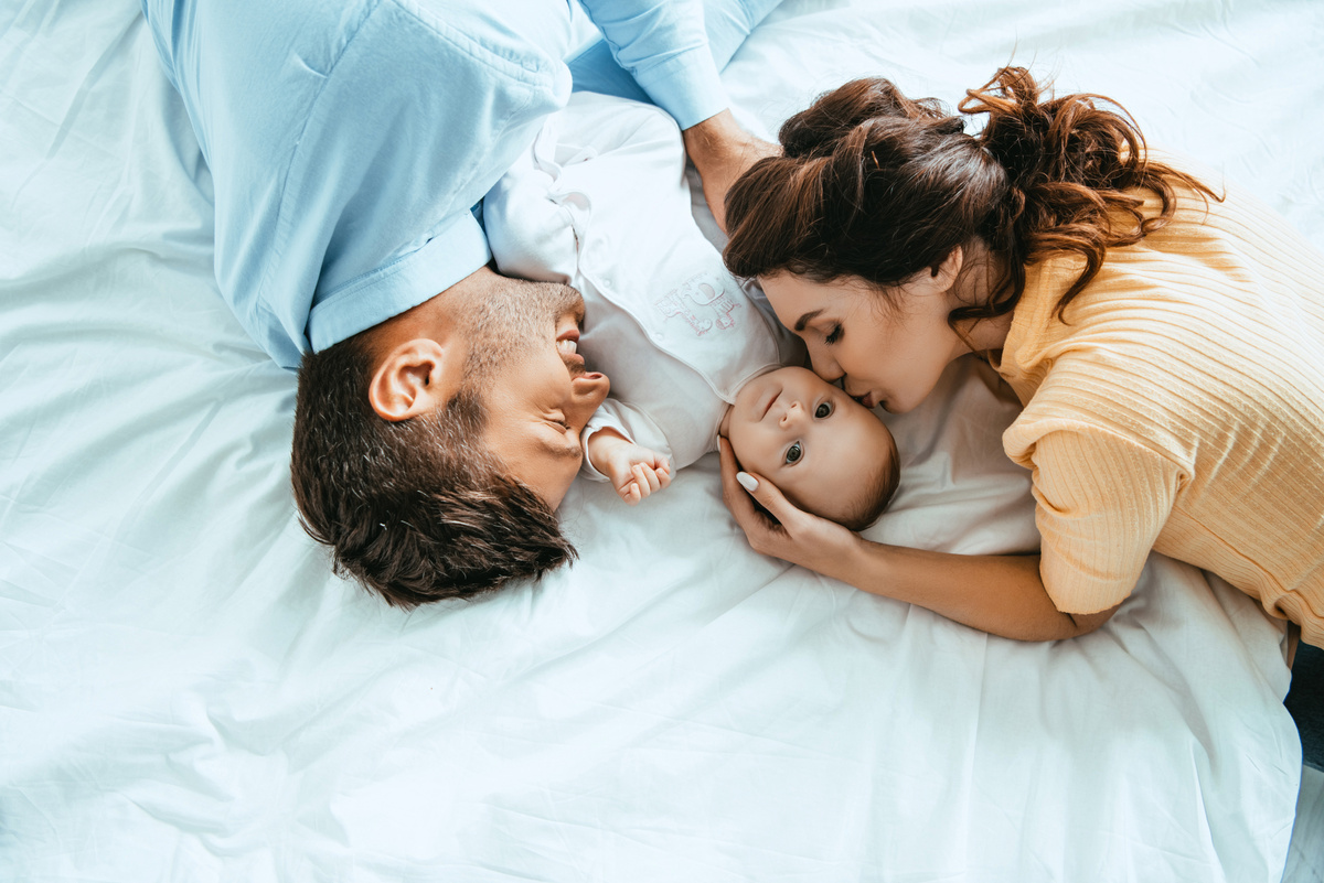 Mamãe e papai deitados na cama com bebê