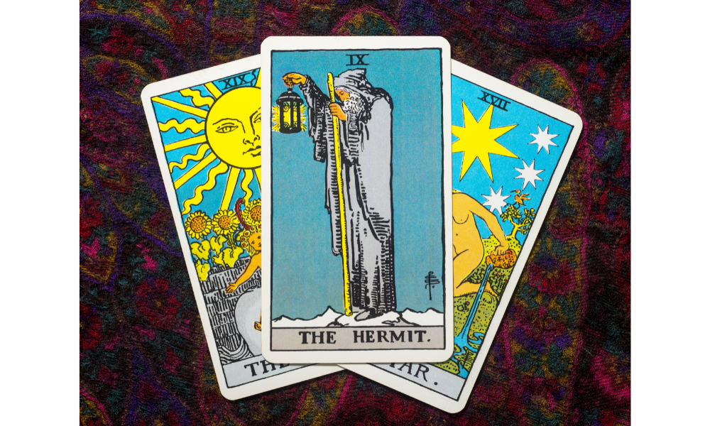 Três cartas de tarot juntas, em destaque a carta O eremita