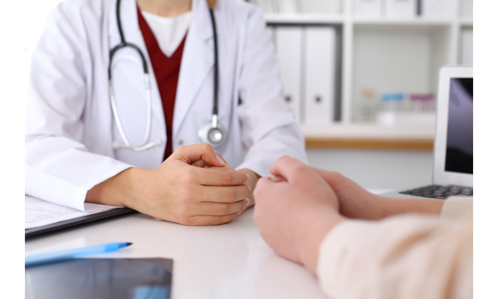 Pessoa sentada e de frente para uma médica, foto sem mostrar o rosto das pessoas.