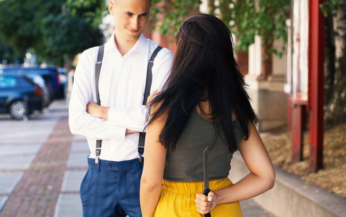 Mulher conversando com homem segurando faca nas costas.