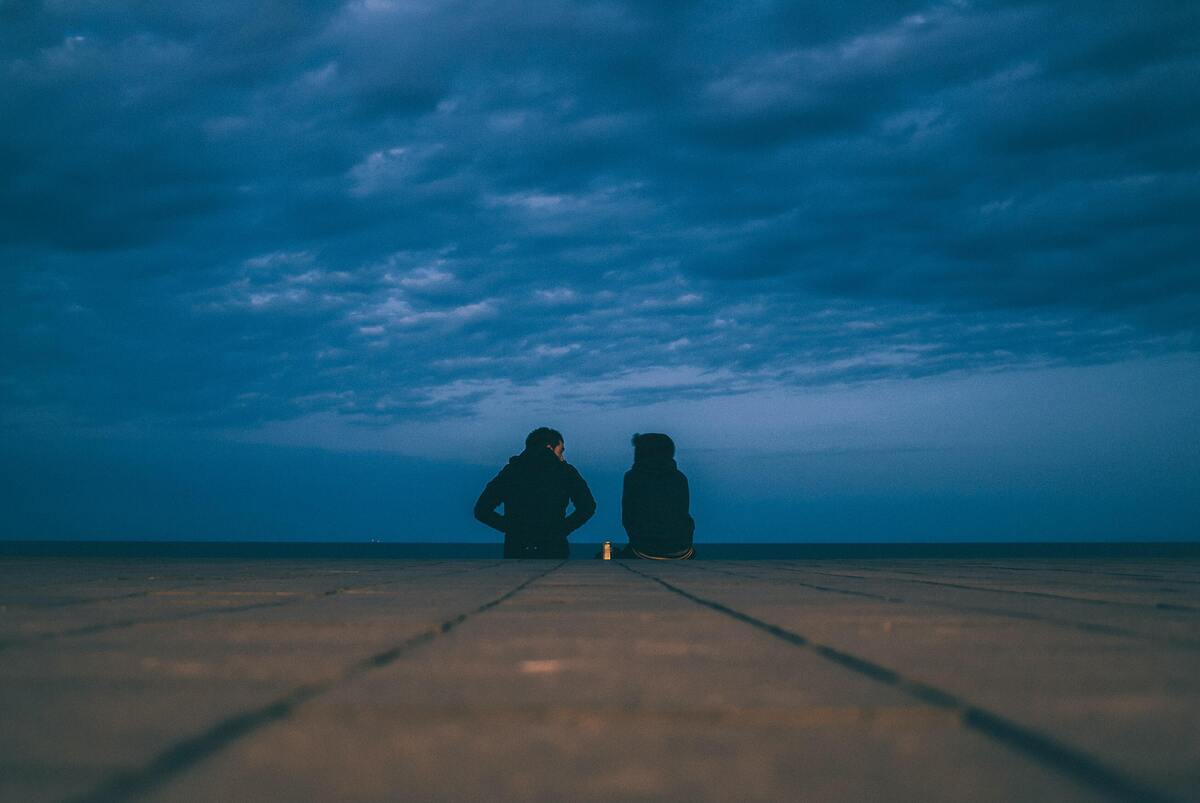 Casal sentado em um campo de areia.