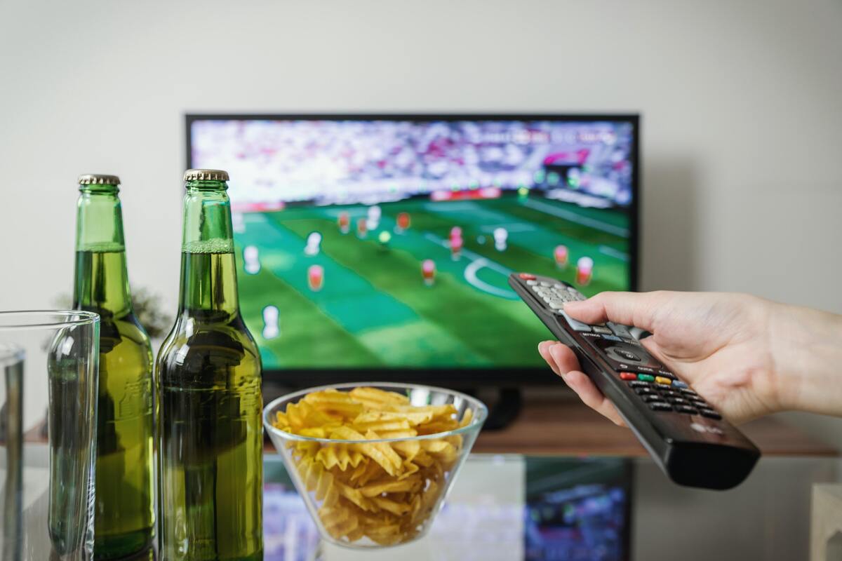 Pessoa assistindo jogo de futebol na TV