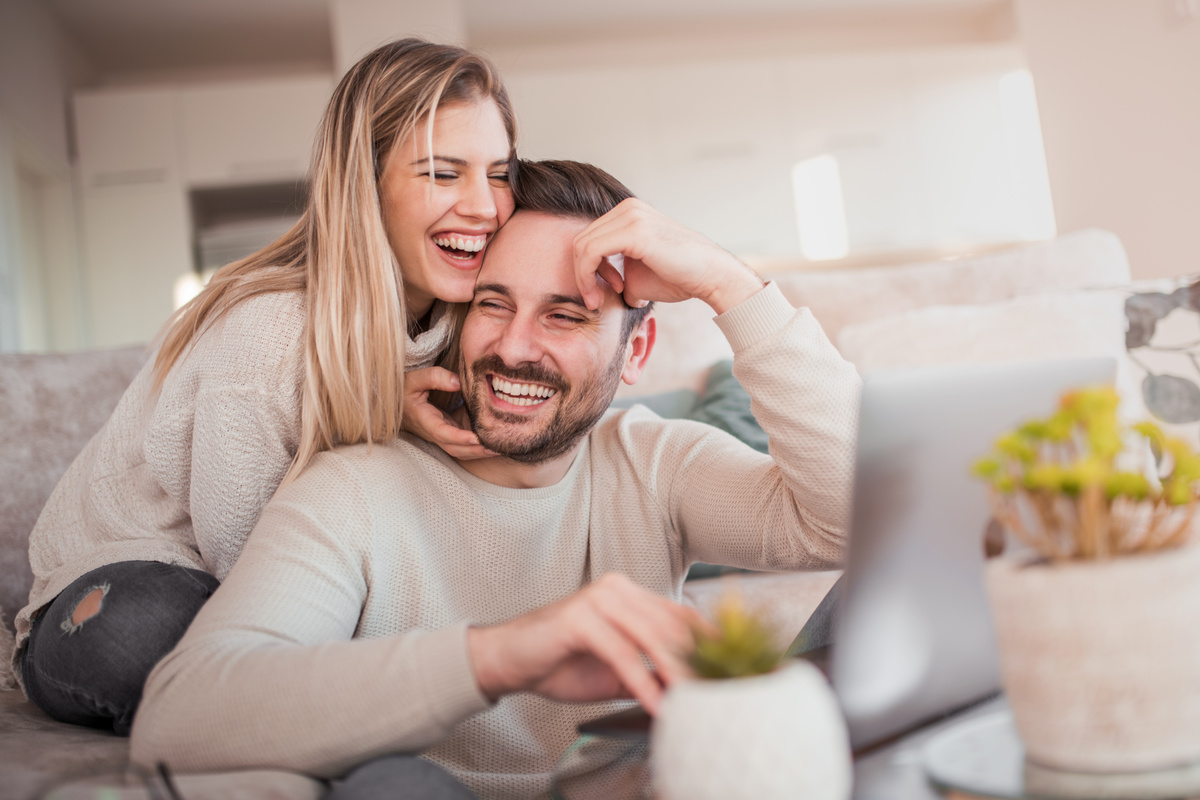 Casal sorrindo em frente ao notebook