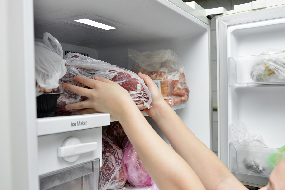 Mãos retirando carne do congelador