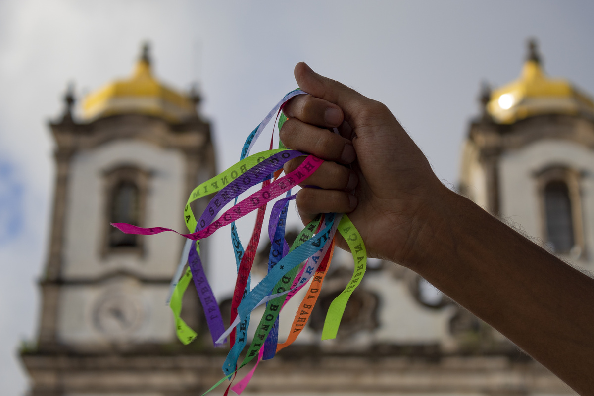 Mão segurando fitinhos do Senhor do Bonfim, da Umbanda, representando a oração.