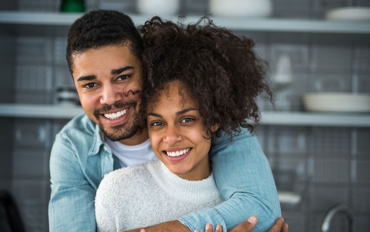 Casal de homem e mulher abraçados e sorrindo.