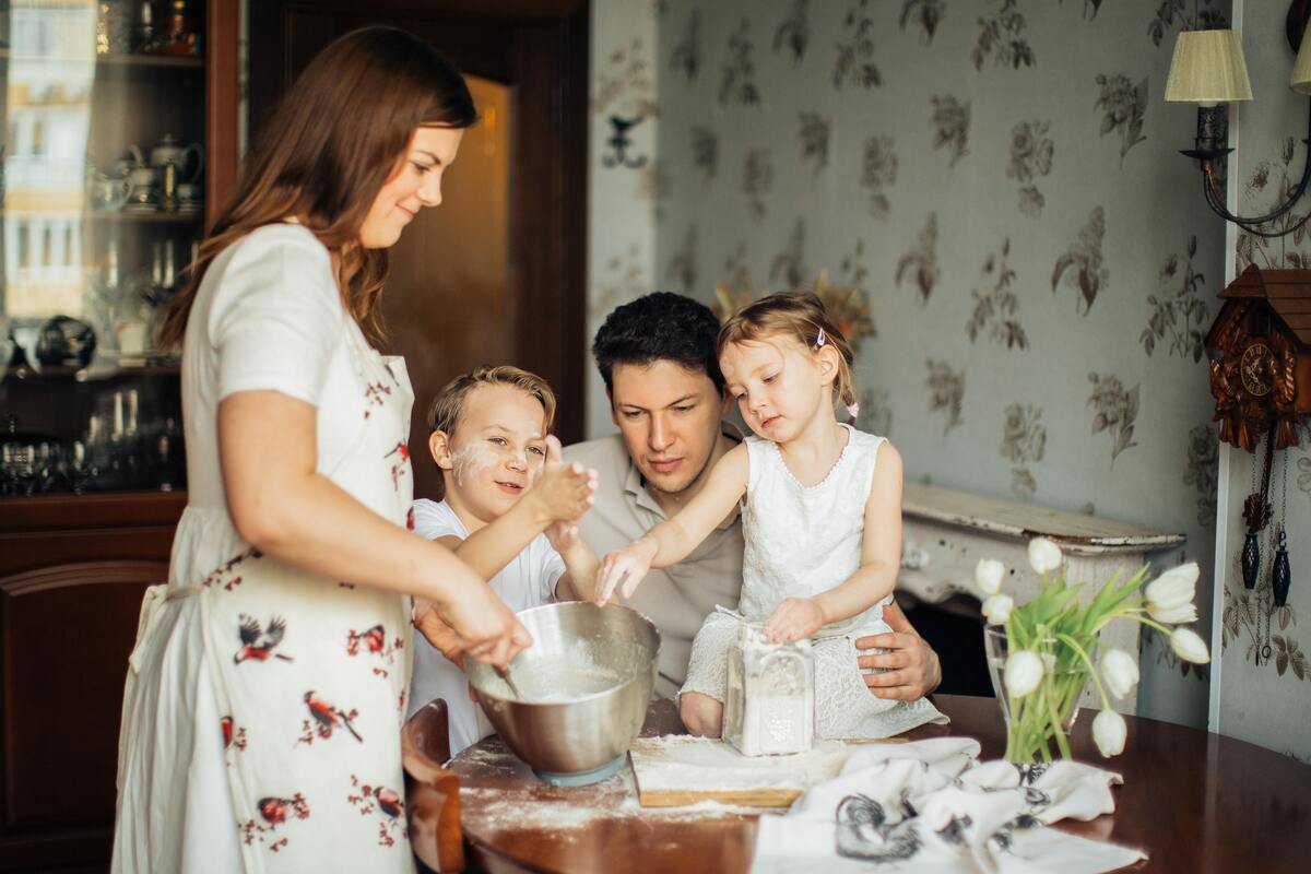 Uma família fazendo bolo e muita farinha esparramada