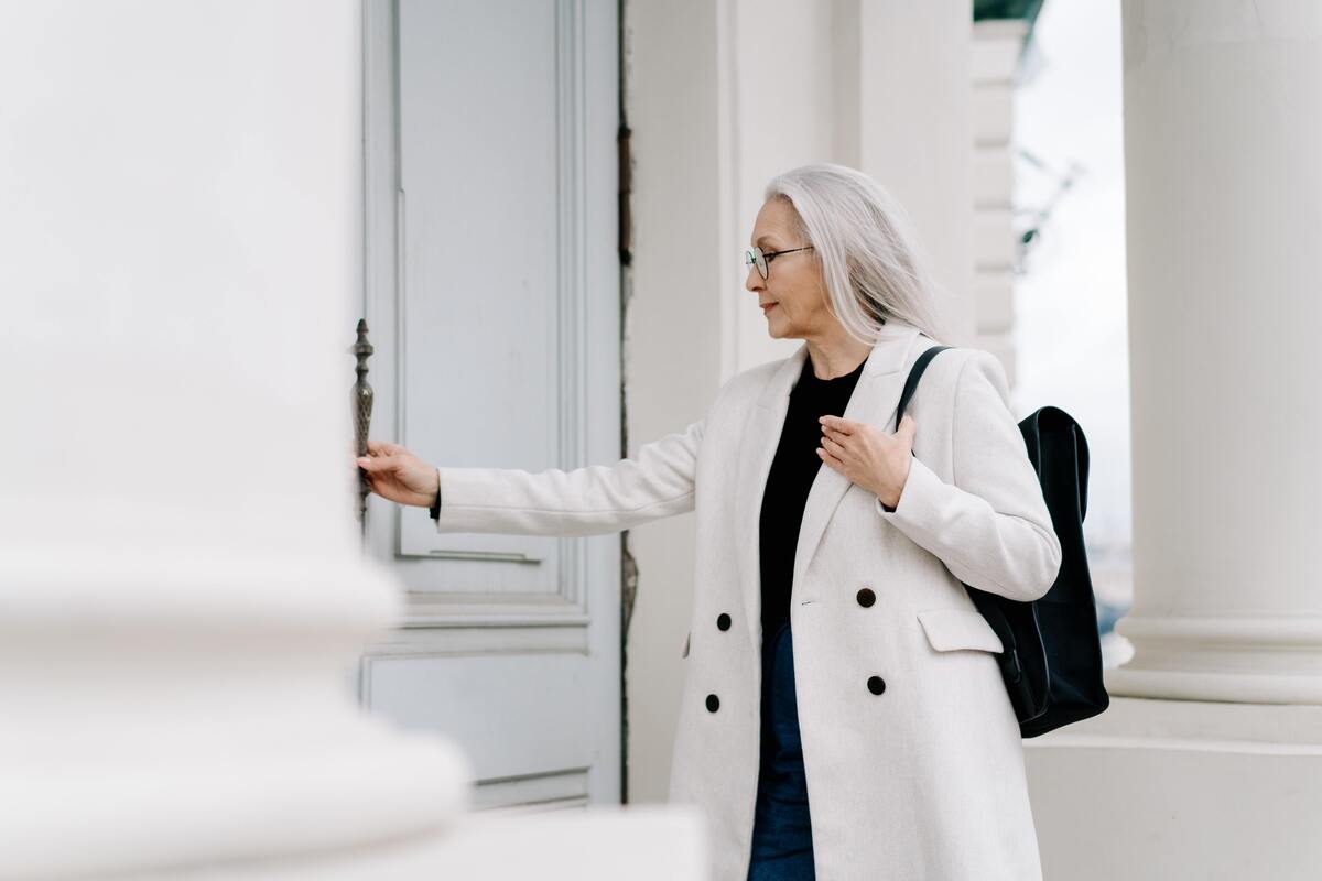 Uma mulher com mochila nas costas abrindo uma porta