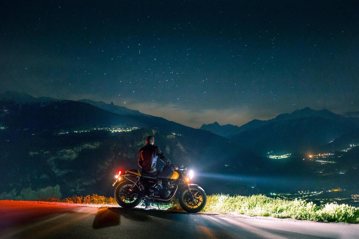 Homem sentado em uma moto, observando uma paisagem.