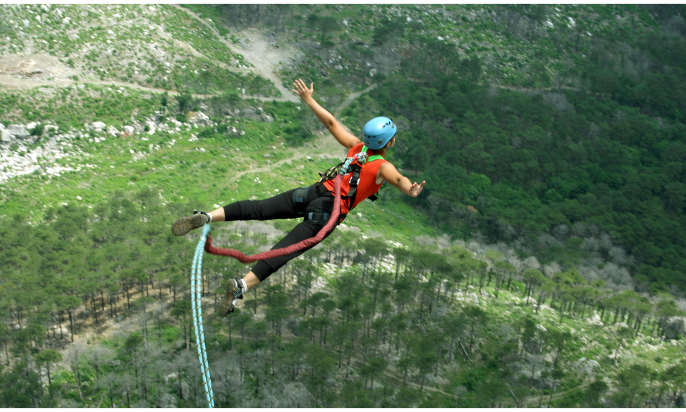 Mulher pulando de Bungee jumping, embaixo terra e grama.