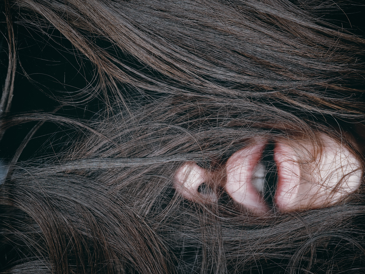 Muito cabelo moreno no rosto de mulher