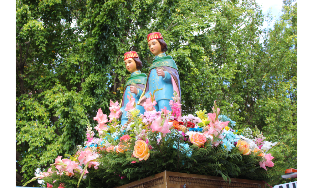 Esculturas de Cosme e Damião sobre flores.