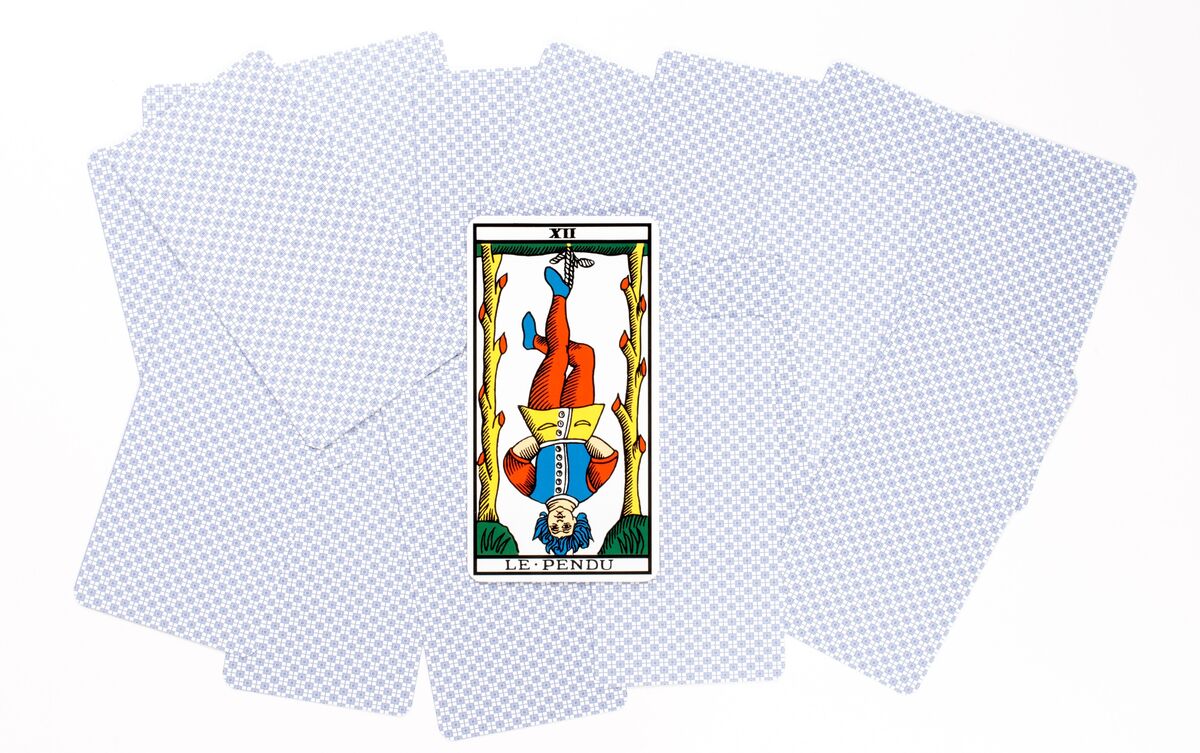 Carta O Enforcado do Tarot sobre outras cartas viradas.