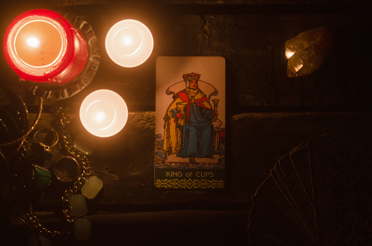 Carta "king of cups" (rei de ouros) ao lado de velas