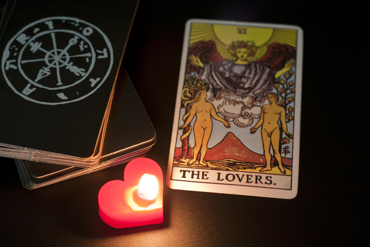 Carta de Tarot "Os Enamorados" ao lado de vela de coração