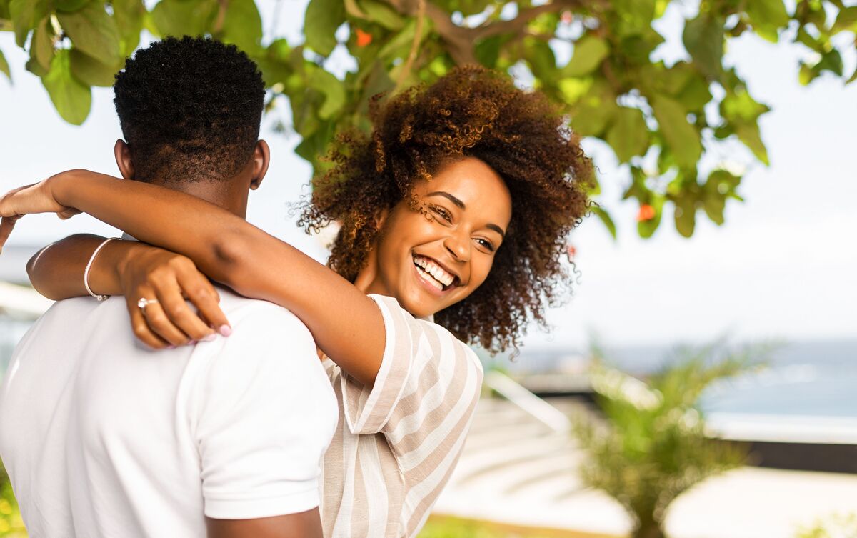 Homem e mulher abraçados e sorrindo em parque.