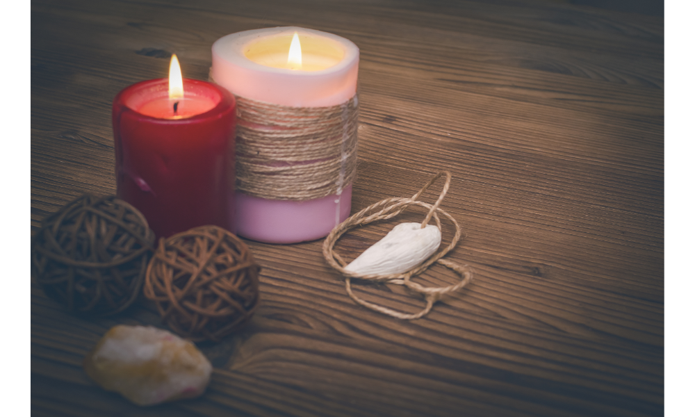 Velas, pedra e novelo de linha sobre uma mesa de madeira.