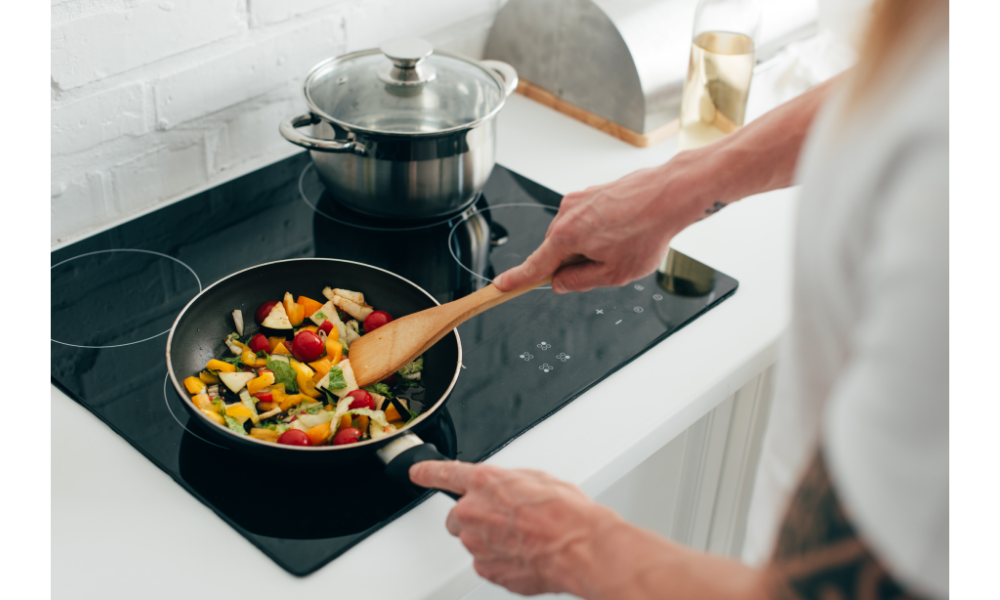 Pessoa cozinhando com uma frigideira em um cooktop.