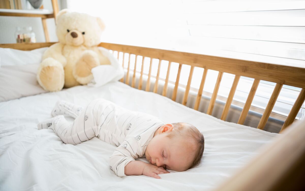 Bebê dormindo em berço de madeira.